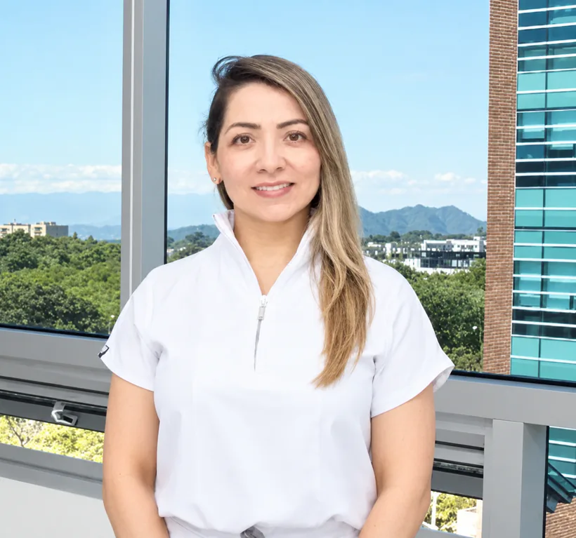 La Dra. Diana Cardozo sonriendo en su consultorio, con vista a las montañas de Ibagué